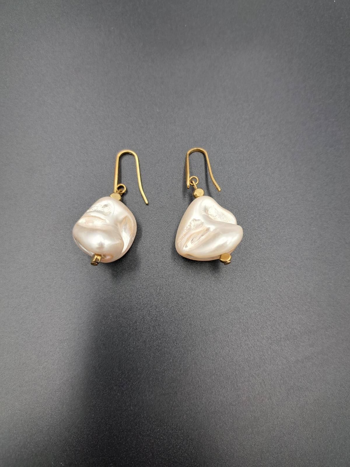 Baroque pearl drop earrings with gold hooks on black background