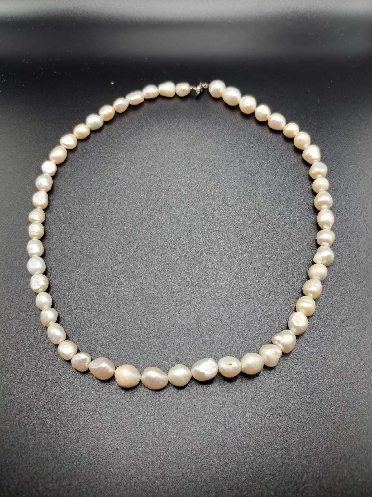 Classic white baroque pearl necklace with silver clasp on black background