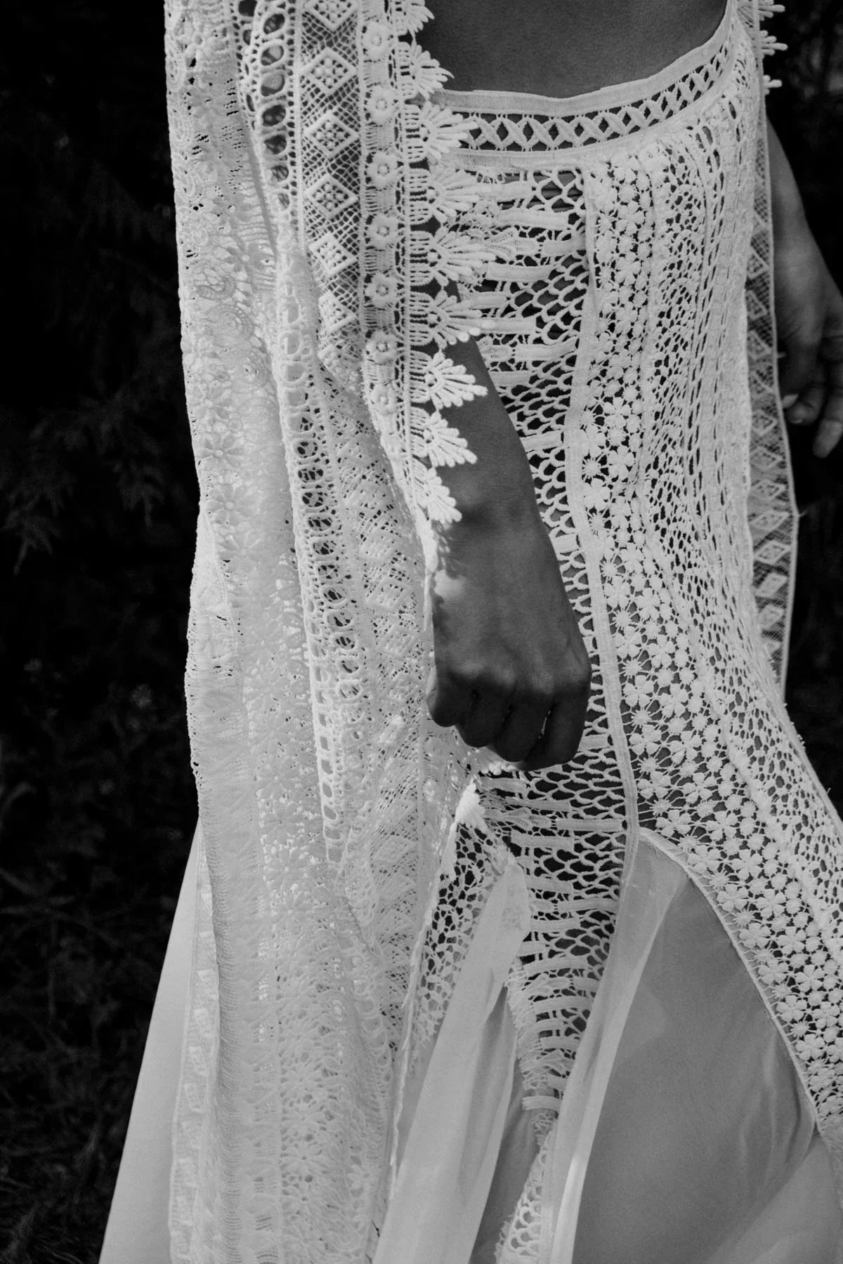 Close-up of a person wearing a detailed white lace dress with intricate floral and geometric patterns