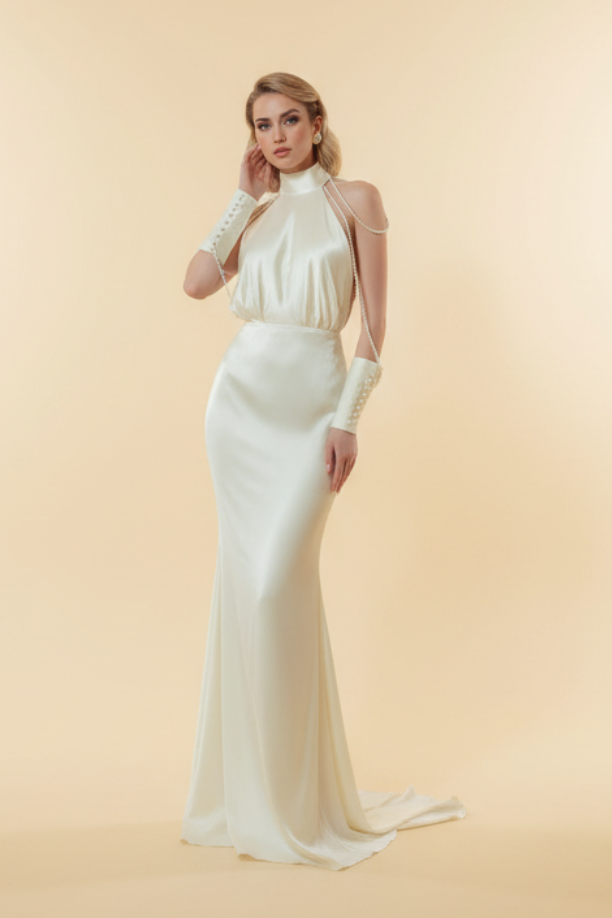 Woman in a white dress standing in an elegant room with a chandelier.