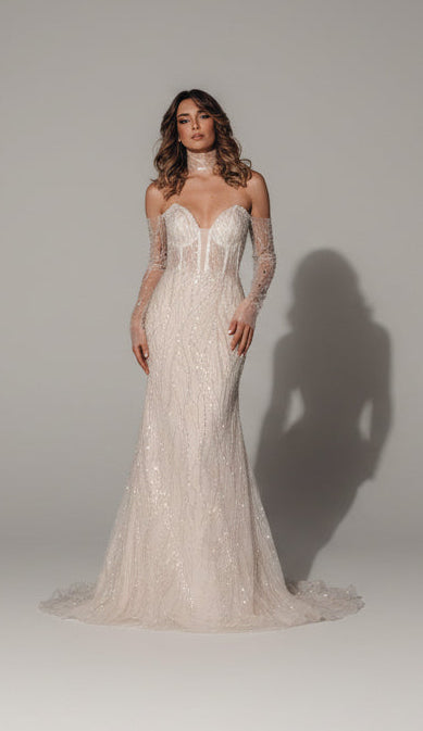 Woman in a white lace wedding dress standing on a dark background