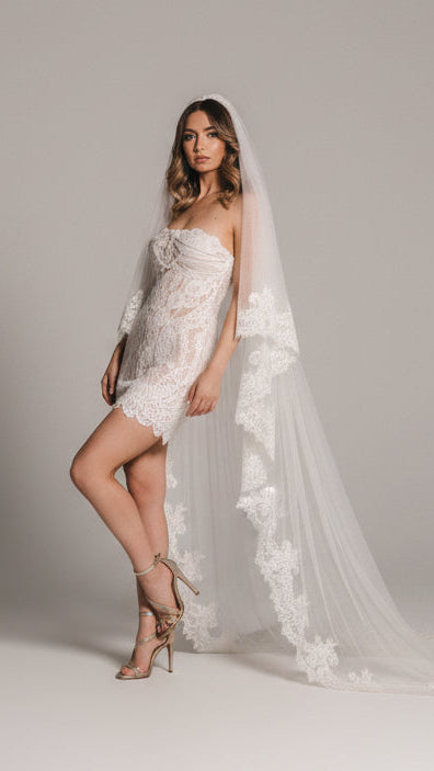 Woman in a wedding dress standing on wooden stairs with a veil.