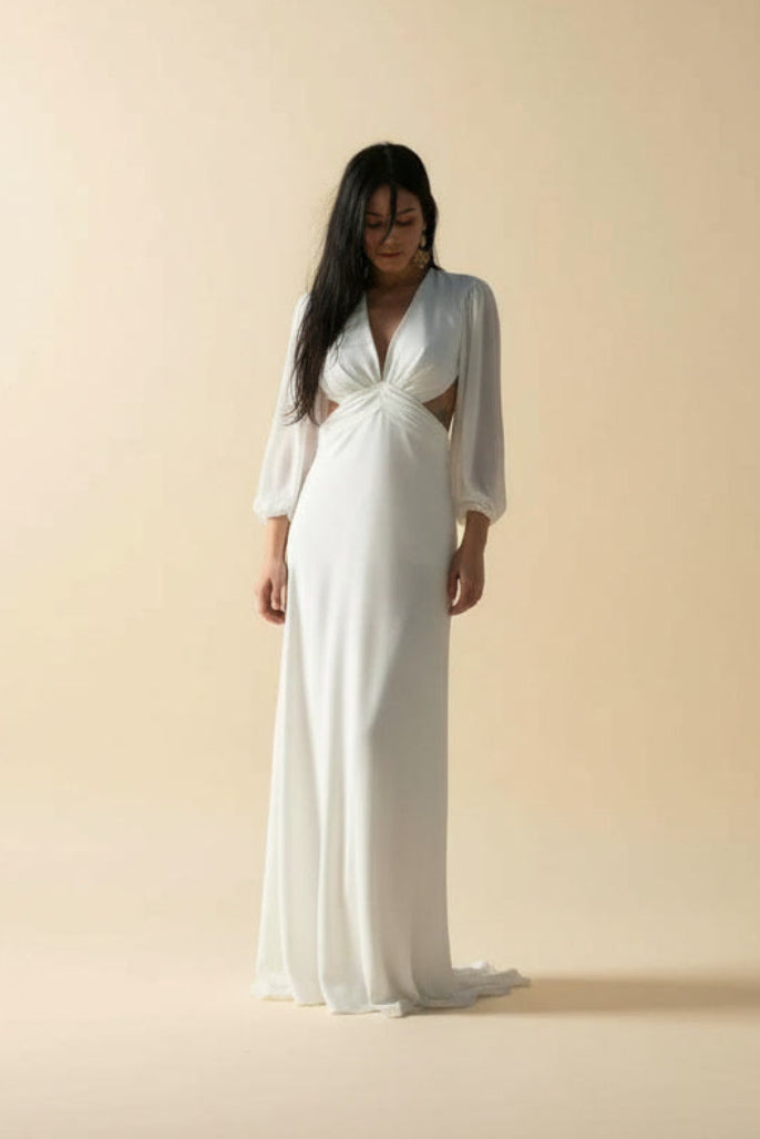 Woman wearing a white dress with cut-out design on a beige background