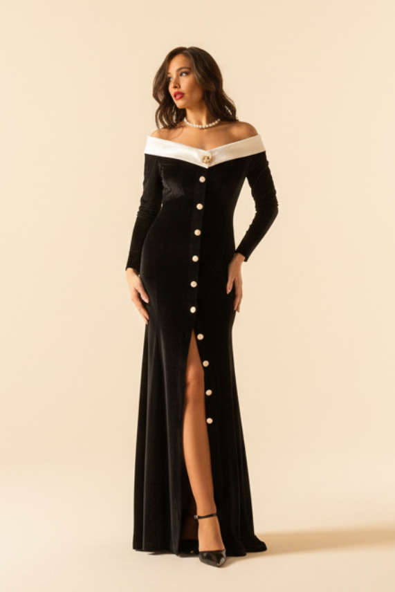 A woman standing in a columned hallway wearing an off-white princess collar black formal dress with golden and white pearl buttons.