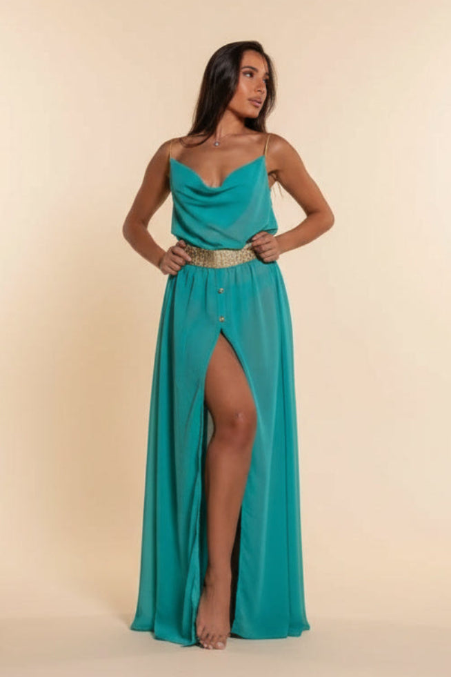 Woman wearing a teal evening gown with a high slit on a beige background