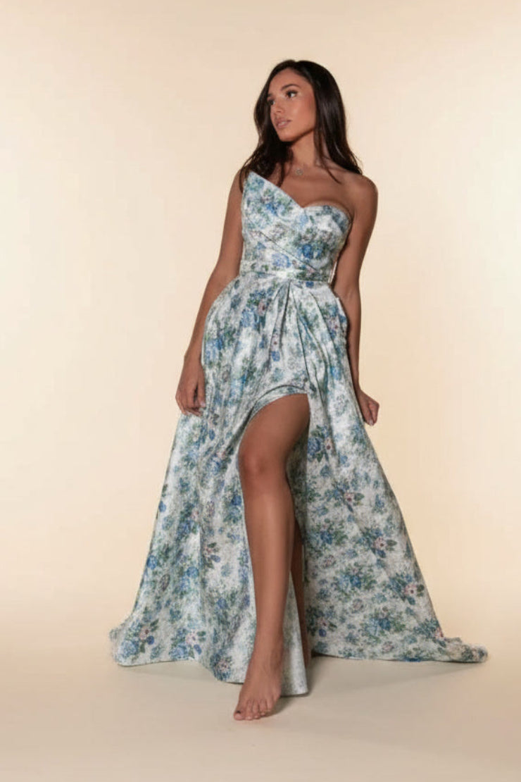 Woman wearing a floral strapless dress with a high slit on a beige background