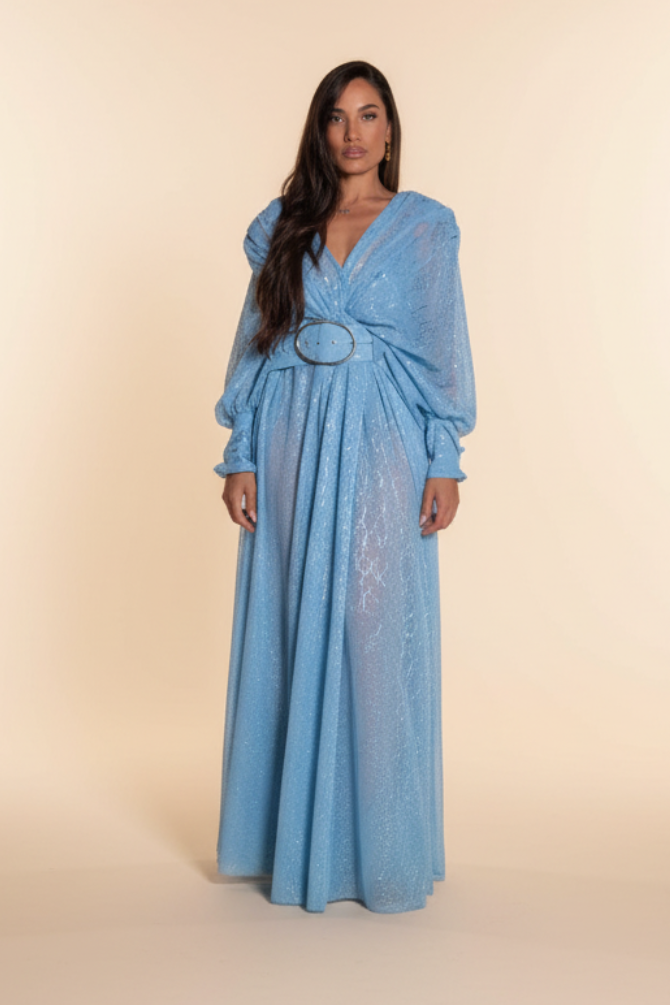 Woman in a blue dress standing in front of rocky terrain