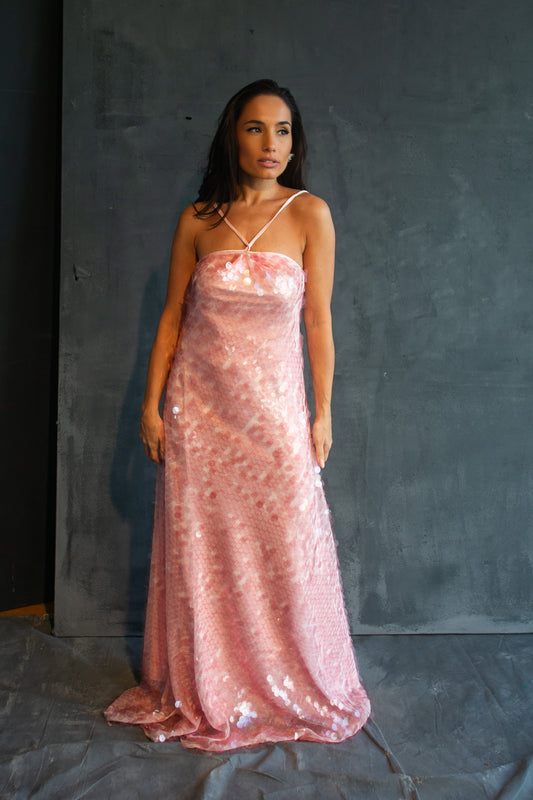Woman wearing a pink sequin dress against a dark background