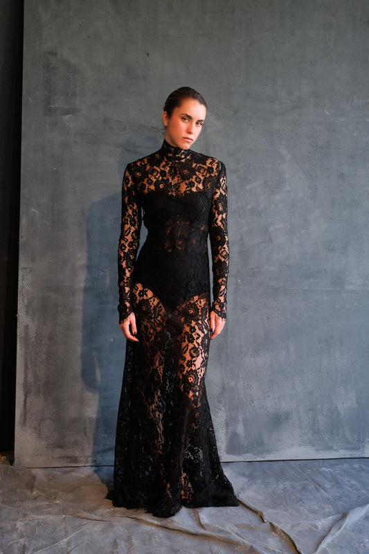 Woman wearing a black lace dress against a gray background